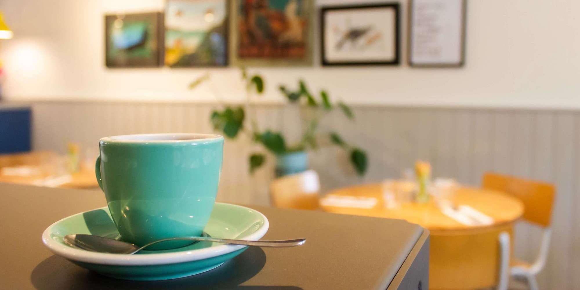 Photo showing a cup and saucer on a table in a cafe. Image from Unsplash (Photographer - Louis Hansel)