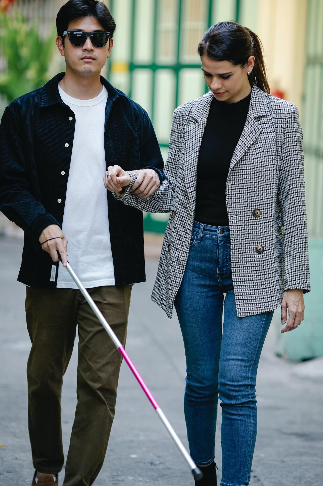 A young lady helping a blind young man with a white stick (image from Pexels by Eren Li-7188740)